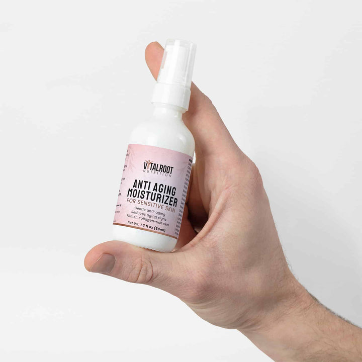 Hand holding a bottle of Vitaloot Anti Aging Moisturizer for Sensitive Skin against a white background