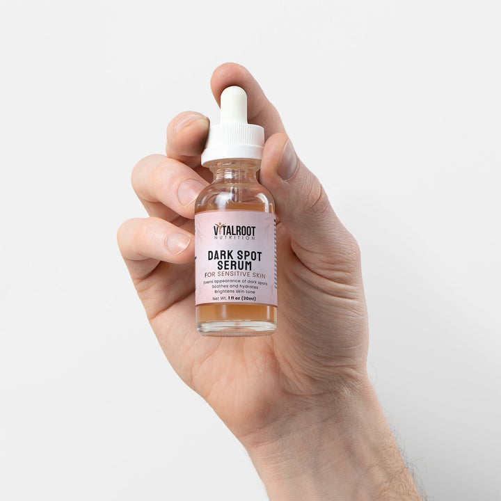 Hand holding a bottle of Vitalicot Dark Spot Serum against a plain background