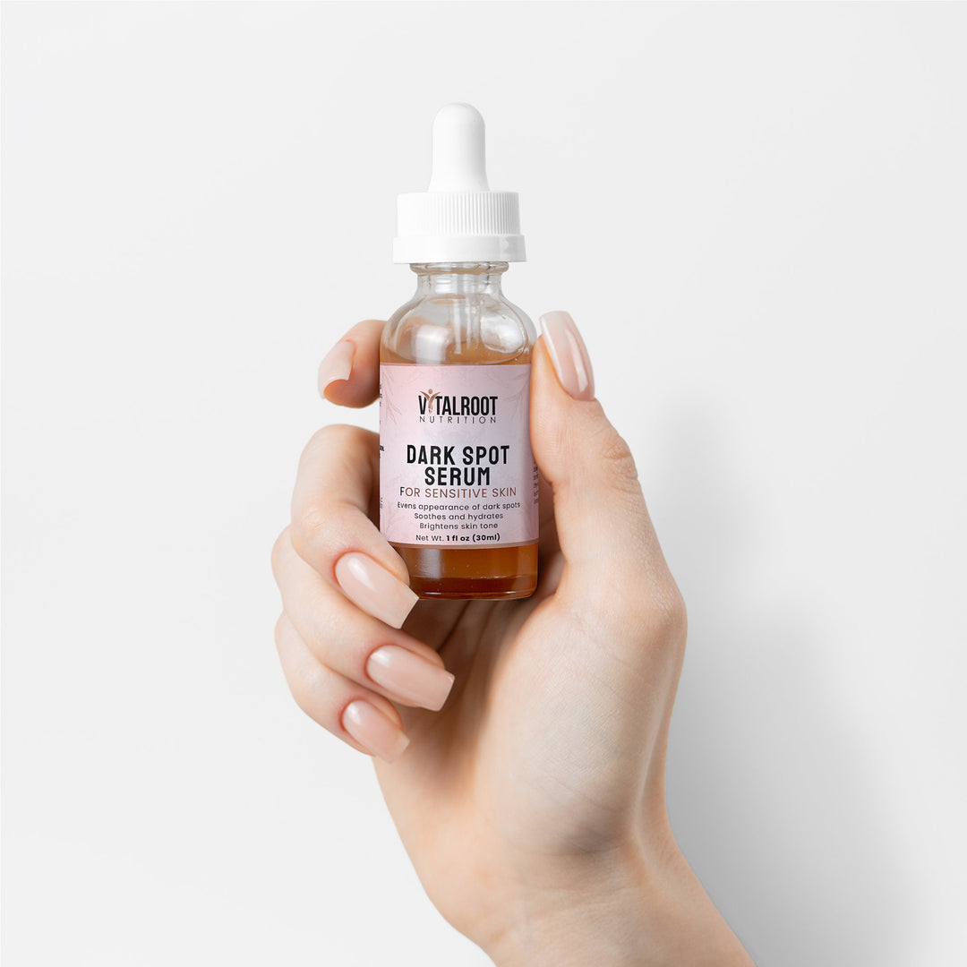 Hand holding a bottle of V'Talroot Dark Spot Serum against a light background