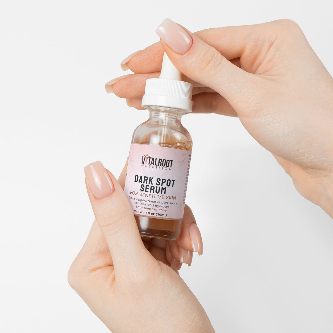 Hand holding a bottle of Vitalroot Dark Spot Serum against a white background