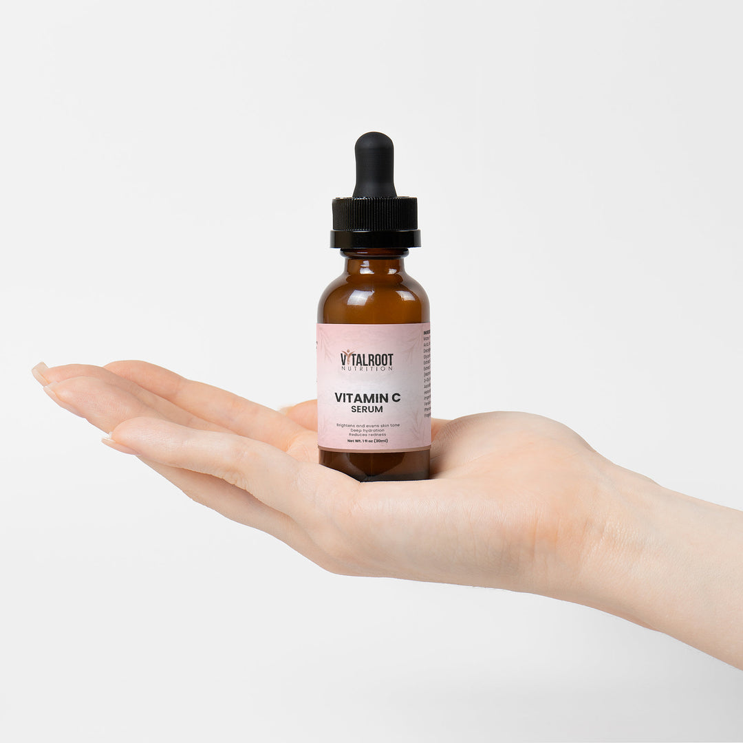 Vitamin C serum bottle held in a hand against a light background