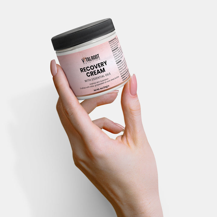 Hand holding a jar of Vital Root Recovery Cream against a light background