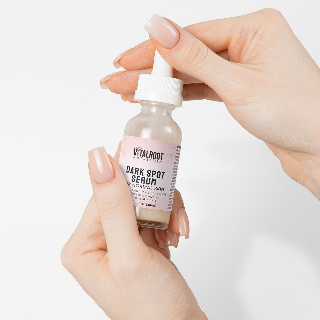 Hand holding a bottle of Vitaloot Dark Spot Serum against a white background