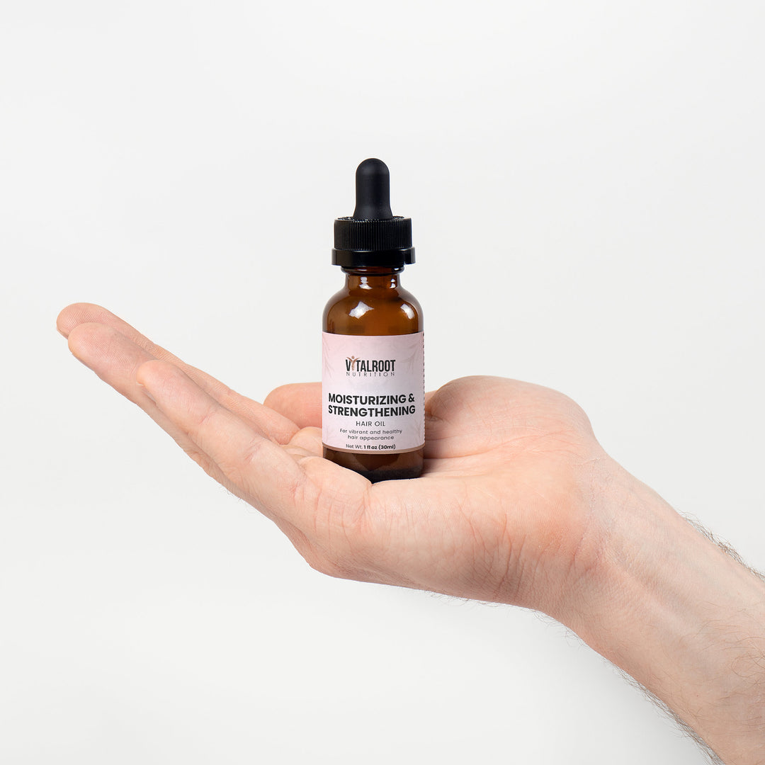 Hand holding a bottle of Vital Root moisturizing and strengthening serum against a white background