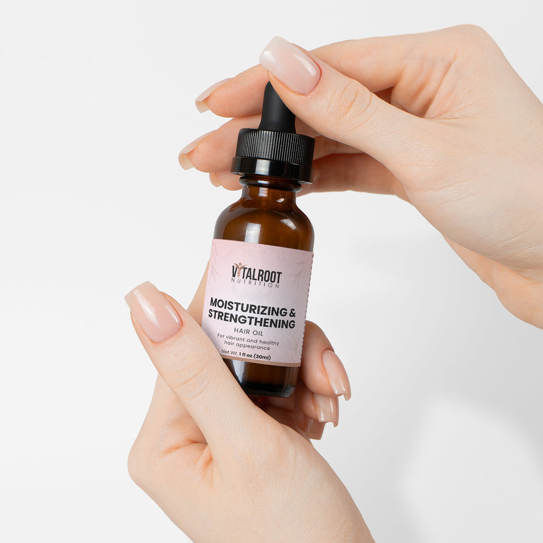 Hand holding a bottle of Vital Root skincare serum with a white background
