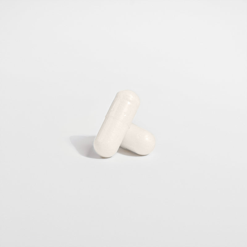 Close-up of 5-HTP capsules on white background with focus on two capsules.