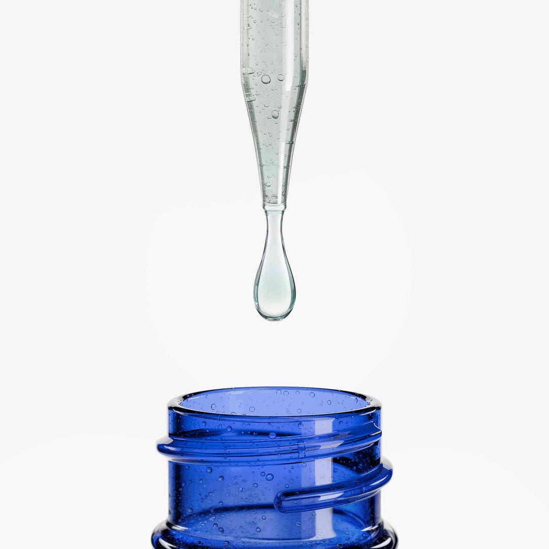 Glass dropper with a drop of liquid above a blue container on a white background