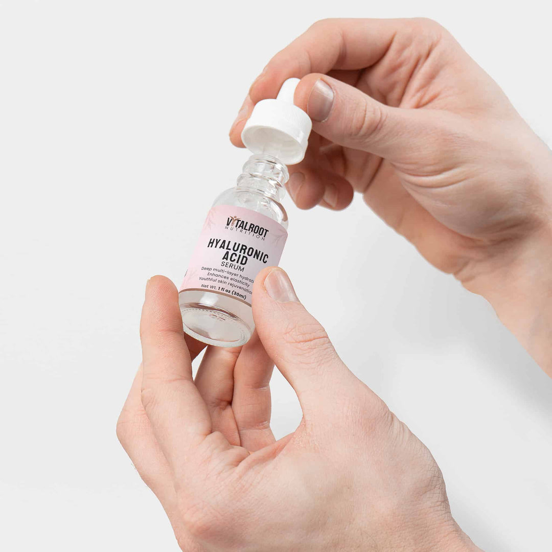 Hand holding a bottle of Vitalorb Hyaluronic Acid serum against a light background