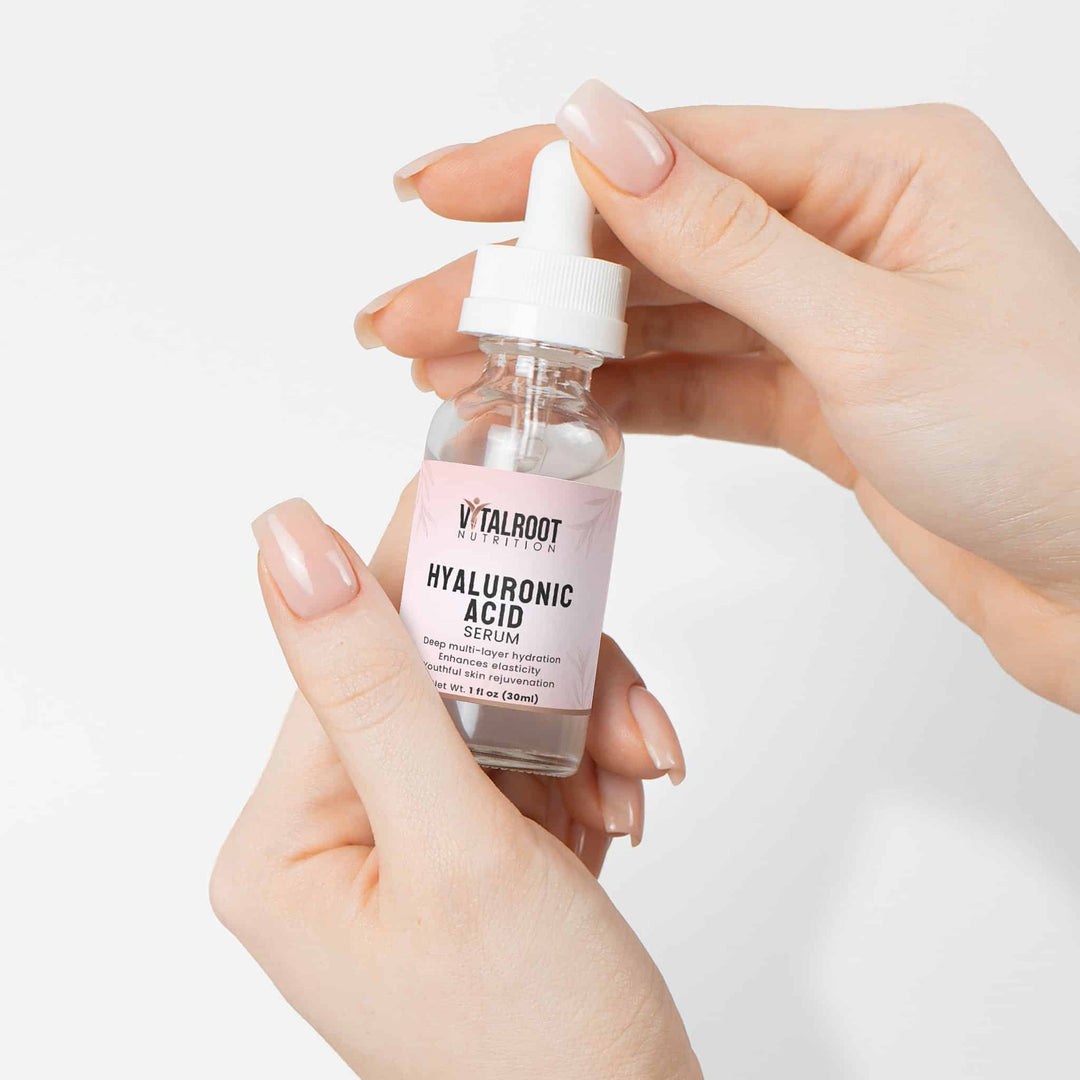 Hand holding a bottle of Vitalroot Hyaluronic Acid serum against a white background