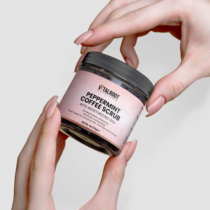 Jar of peppermint coffee scrub held by hands against a neutral background
