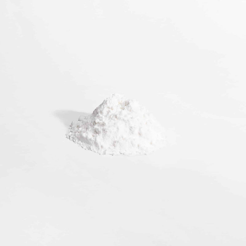 Close-up of L-Glutamine powder with a scoop of powder beside it on a white background.