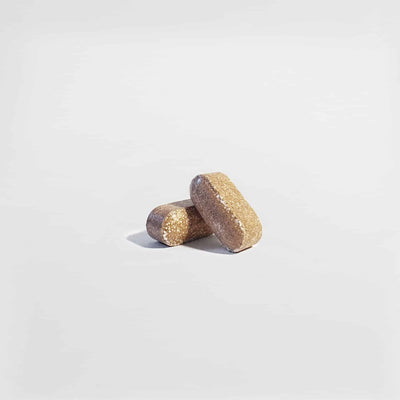 Close-up of two Vital Roots Men’s Vitality tablets, supporting stamina and male wellness