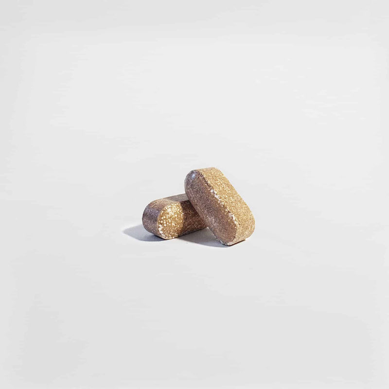Close-up of two Vital Roots Men’s Vitality tablets, supporting stamina and male wellness